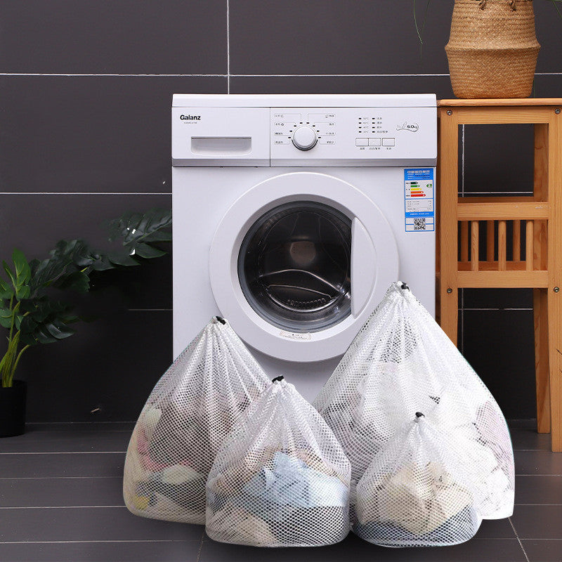 Three mesh laundry bags in front of a washing machine in a laundry room.