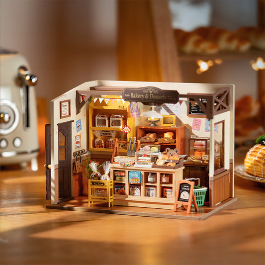 Miniature bakery model with detailed interior on a wooden surface.