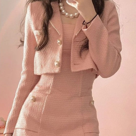 Person wearing a pink suit with pearl buttons against a pink background
