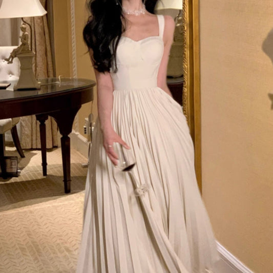 Woman in a white dress holding a glass in an elegant room.