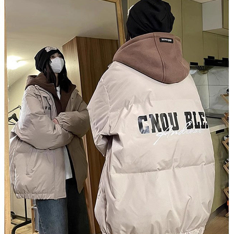 Person wearing a beige puffer jacket with 'CNDW BLEED' text, standing in a room.