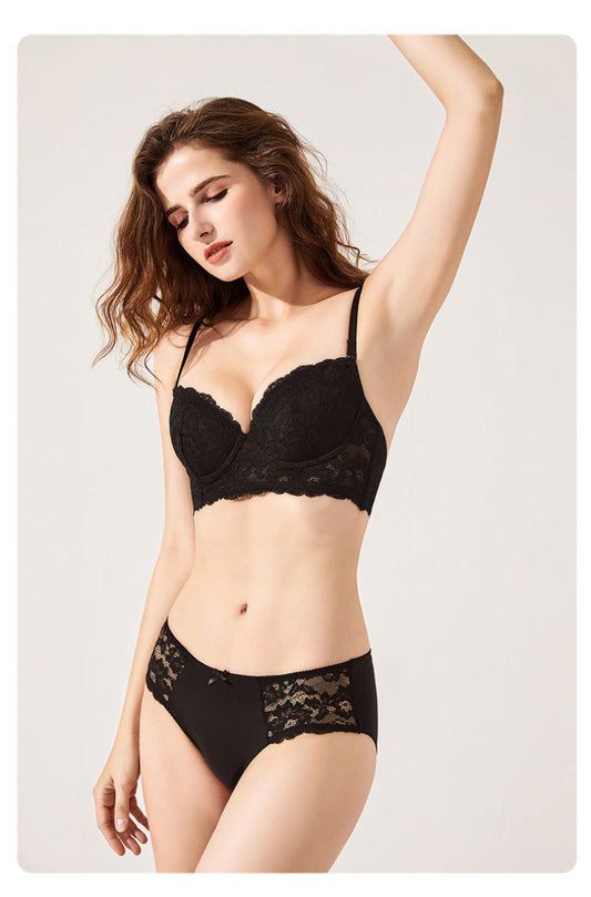 Woman wearing a black lace lingerie set on a plain background