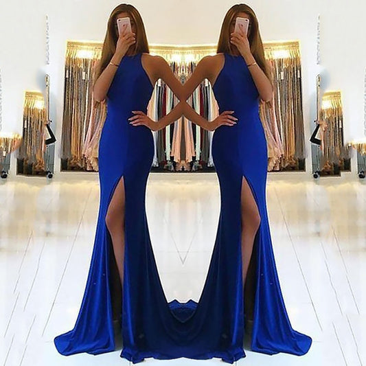 Woman wearing a blue evening gown with a high slit in front of a mirror.
