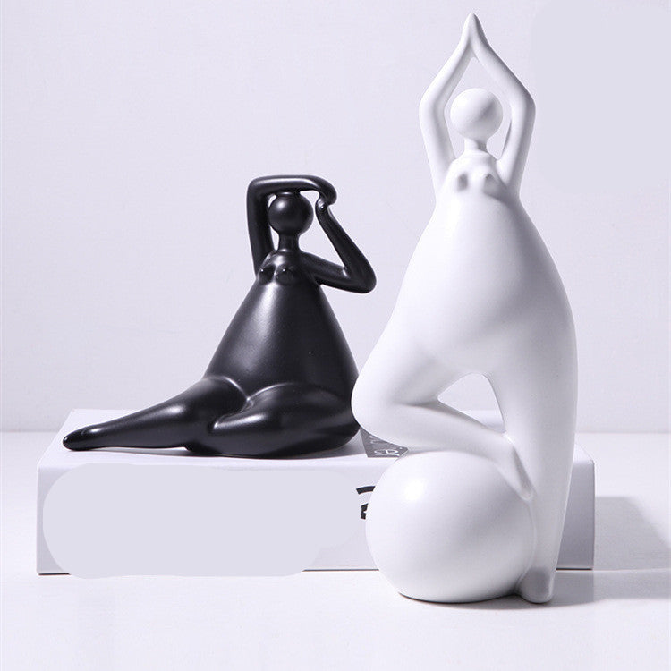 A pair of white ceramic figurines, one sitting and one standing, placed on top of a stack of books with a decorative vase beside them.