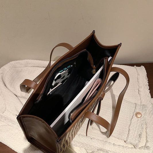 Brown leather handbag with interior organization on a textured surface.