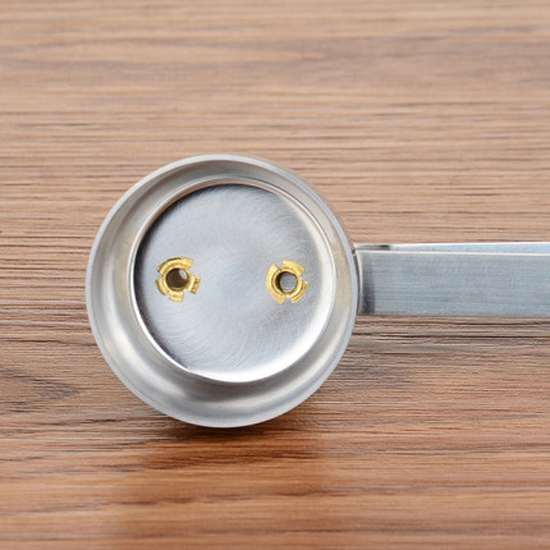 Metallic spoon with a circular head on a wooden surface