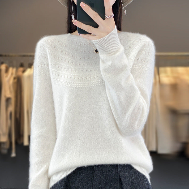 A person wearing a blue crew neck, long-sleeved sweater with a hollow pattern at the collar.