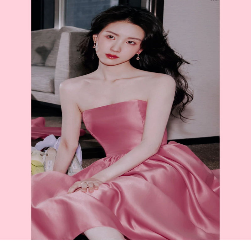 Woman in a pink dress sitting on a couch with a blurred background