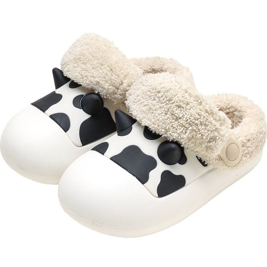Pair of white slippers with black cow print and fluffy beige interior on a white background