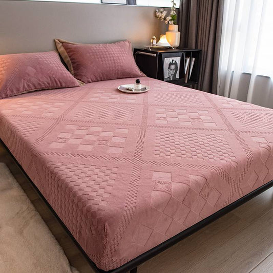 Pink quilted bedspread and pillows on a bed in a bedroom.
