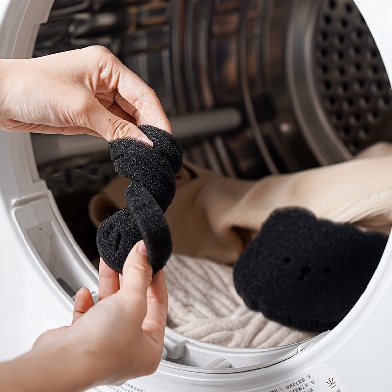 Person holding black socks in front of an open washing machine.