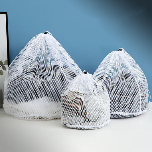 Three white mesh laundry bags on a light surface with a blue background