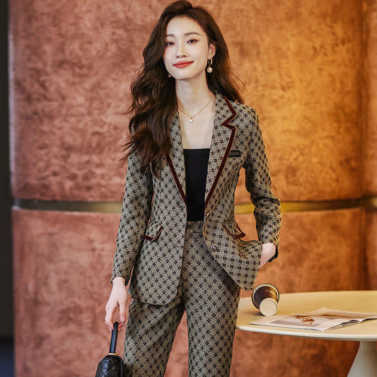 Woman in a patterned suit standing in front of a textured wall.
