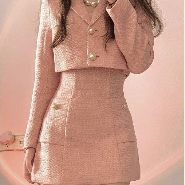 Person wearing a pink textured outfit with a matching handbag against a soft pink background