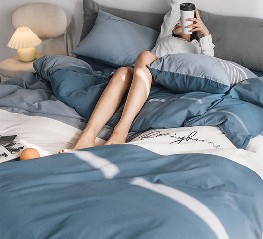 A bed with a blue and white bedsheet, a yellow quilt cover, and matching pillows, with a newspaper and a apple placed on the bed.
