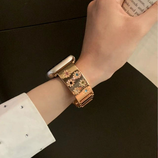 Gold bracelet with floral designs on a wrist against a dark background