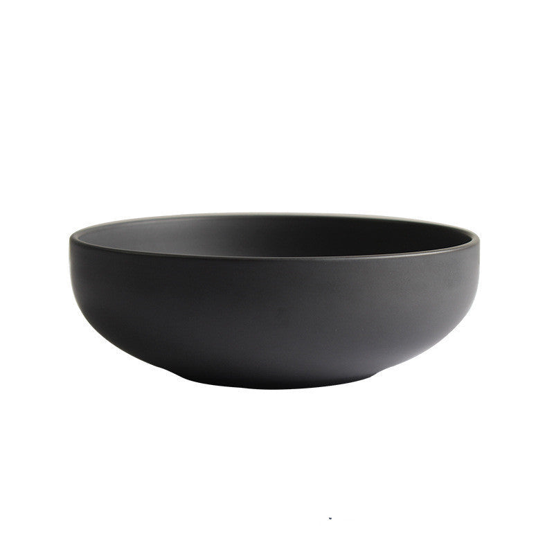 A set of black ceramic dishes including rice bowls, steak plates, and other tableware items arranged on a dark surface.