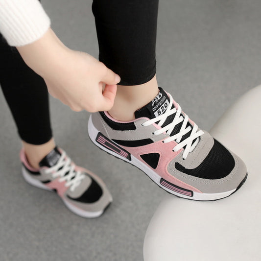 Person wearing pink and gray sneakers with white laces on a neutral background