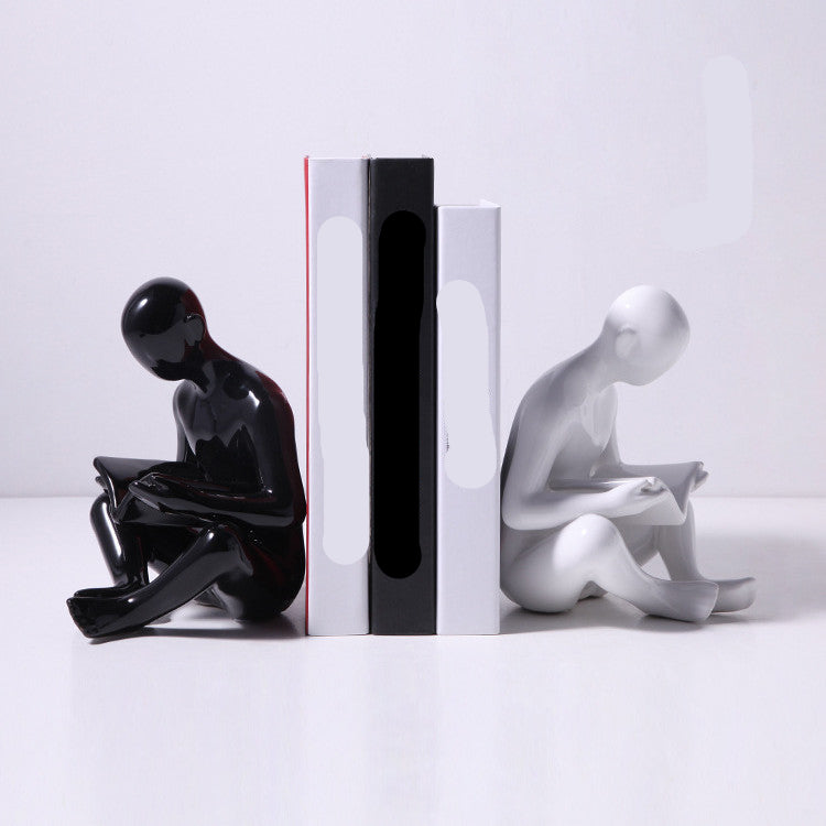 Black and white bookends shaped like sitting figures on books with visible text.