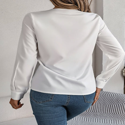Person wearing a white blouse and blue jeans against a neutral background