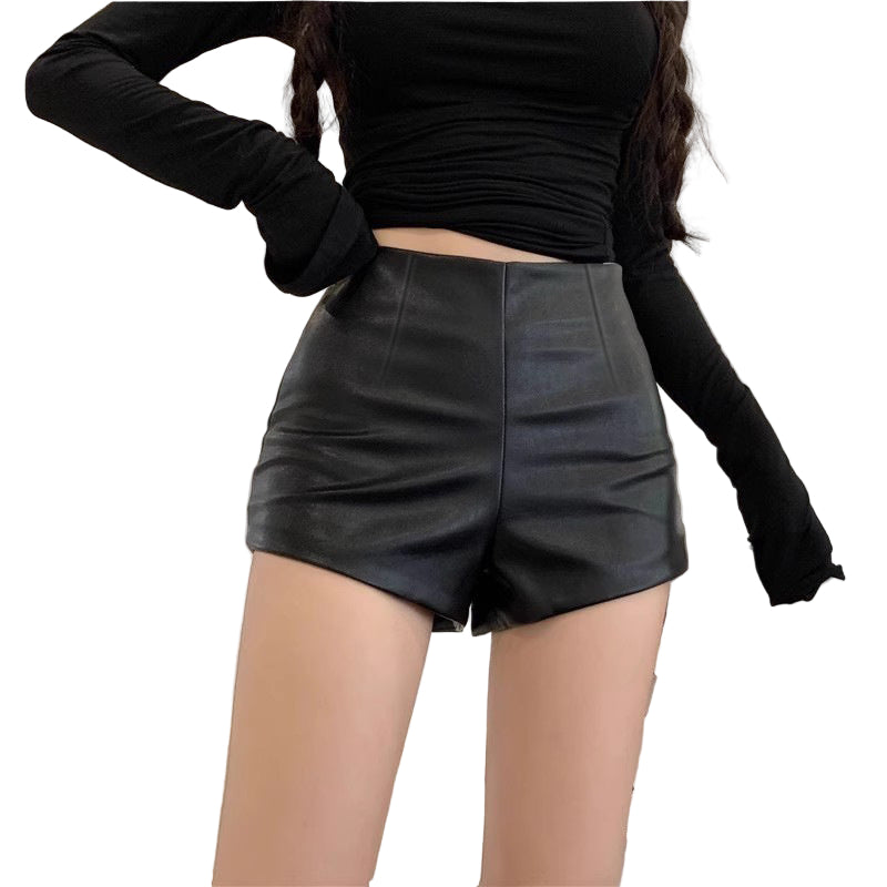 Person wearing black leather shorts and a black long-sleeve top indoors.