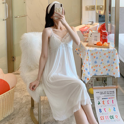 Woman in a white nightgown taking a mirror selfie in a room with a table and bags.