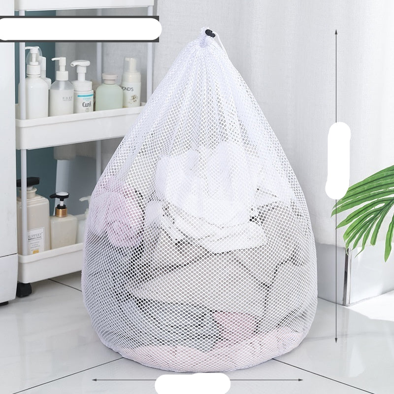 Two white mesh laundry bags filled with laundry standing in front of a washing machine with a person partially visible in the background.