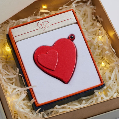 Red heart-shaped object in a gift box with decorative lights in the background