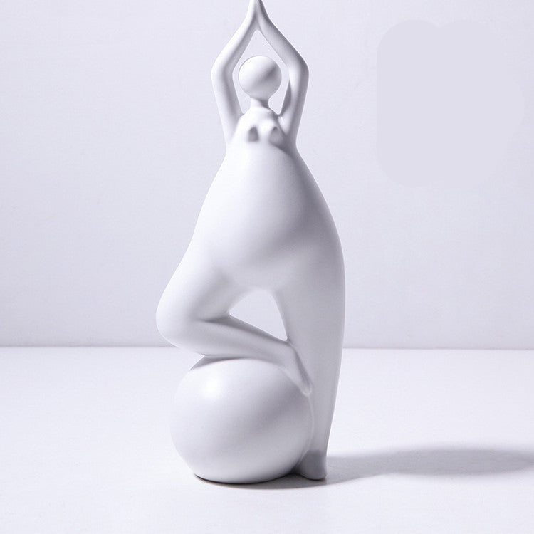 A pair of white ceramic figurines, one sitting and one standing, placed on top of a stack of books with a decorative vase beside them.