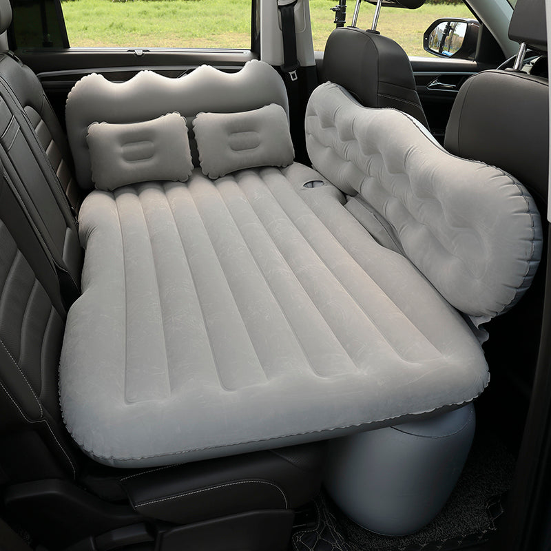 Inflatable car mattress set up in a vehicle with two pillows.