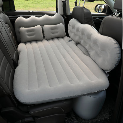 Inflatable car mattress set up in a vehicle with two pillows.