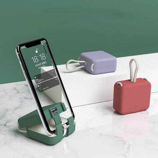 Green phone stand with a smartphone, purple power bank, and red case on a white surface with green background