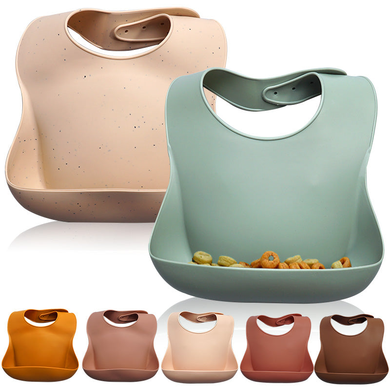 Two silicone bibs, one beige and one green, with a reflection on a white background.