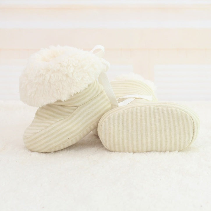 Pair of cream-colored baby shoes on a light background