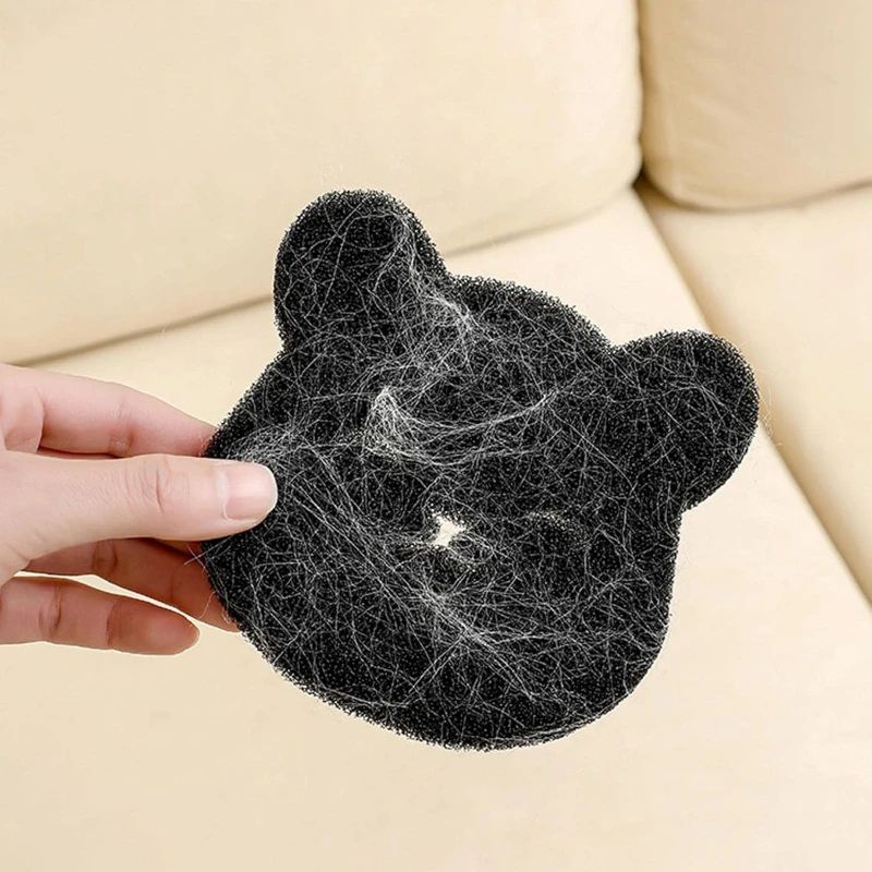 Hand holding a black pet hair removal tool with collected hair against a beige background