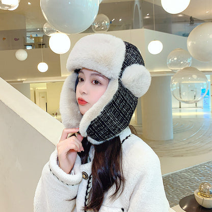 Woman wearing a winter hat and coat in an indoor setting with decorative lights.