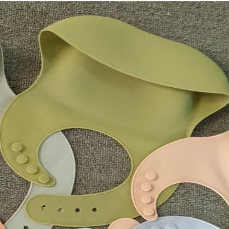 Three colorful silicone bibs on a textured surface
