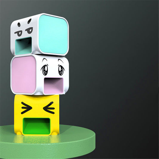 Stack of colorful emoji-like cubes on a green surface with a dark gray background