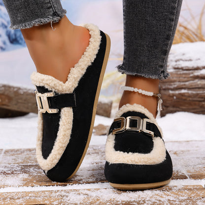 Black and white slip-on shoes with fur trim worn by a person on a snowy background