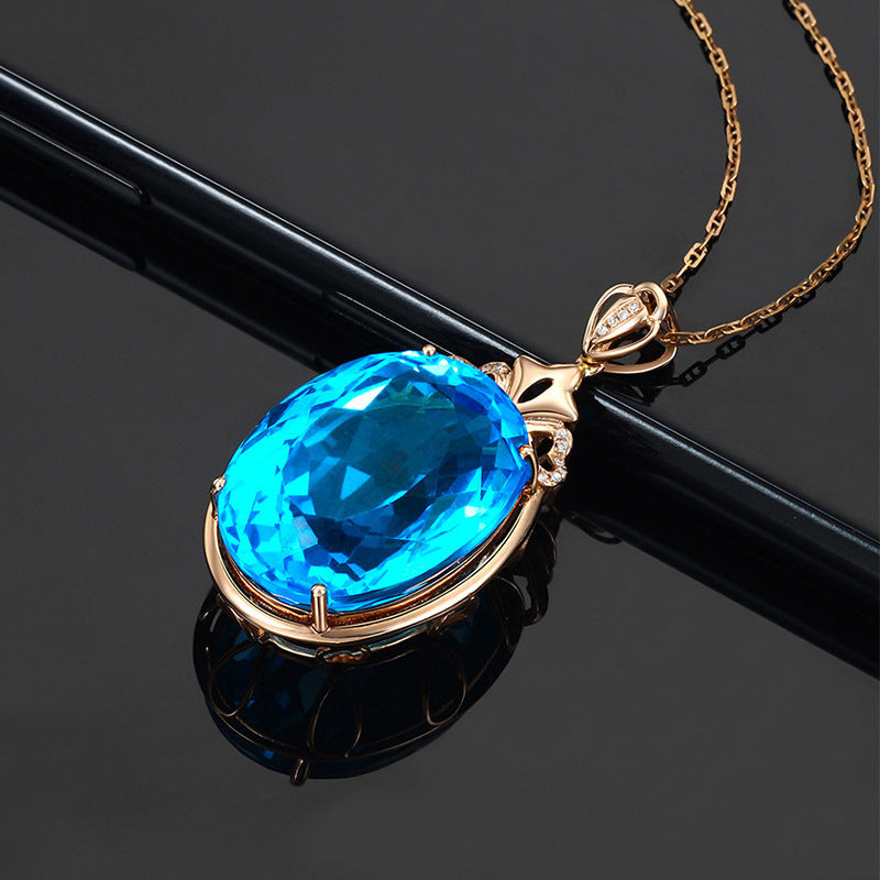 Gold necklace with a blue gemstone pendant on a black background