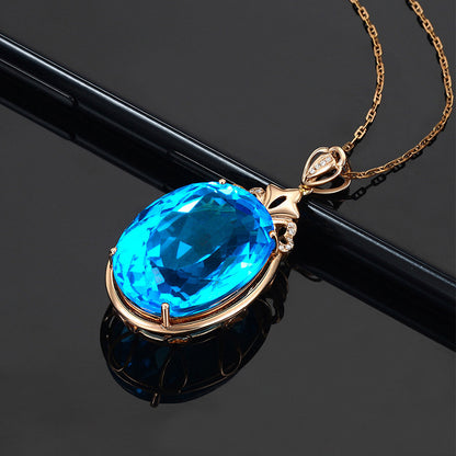 Gold necklace with a blue gemstone pendant on a black background