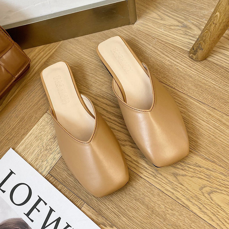 Pair of beige high-heeled shoes on a wooden floor with a magazine underneath.