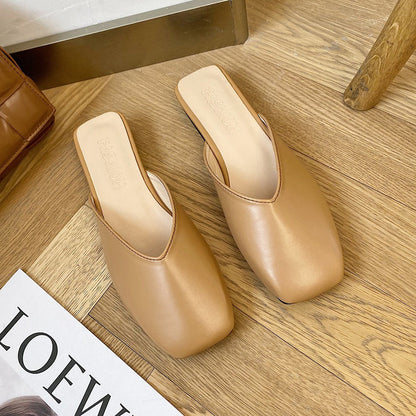 Pair of beige high-heeled shoes on a wooden floor with a magazine underneath.