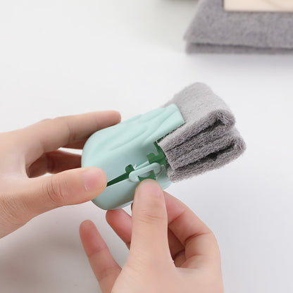 Hand holding a small cleaning tool with a gray scrubber on a light background