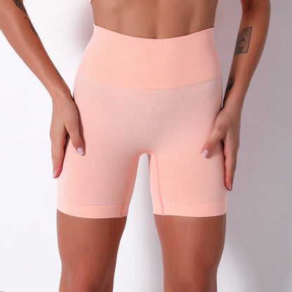 Person wearing light pink high-waisted shorts on a plain background