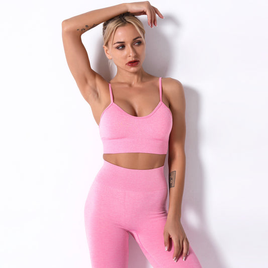 Woman wearing a pink sports bra and leggings set against a white background