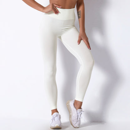 Person wearing white leggings and sneakers on a plain background