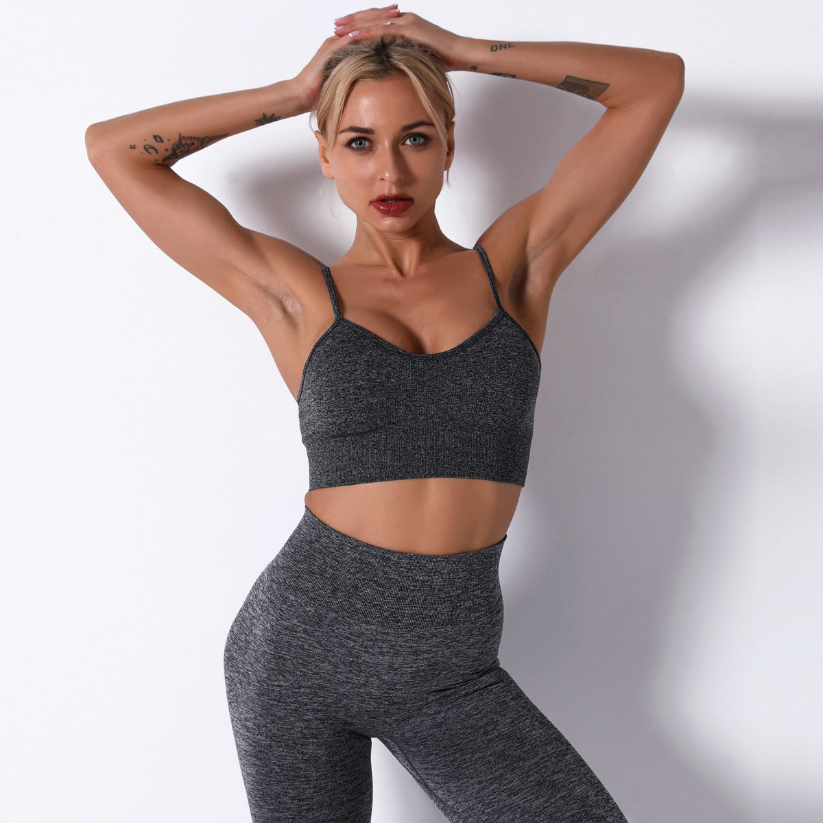 Woman wearing a gray sports bra and leggings against a white background