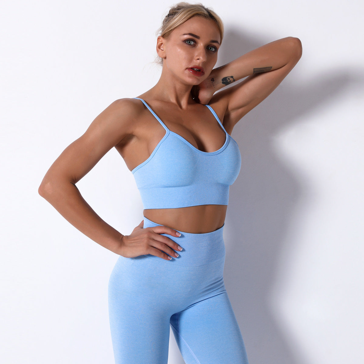 Woman wearing a light blue sports bra and leggings against a white background