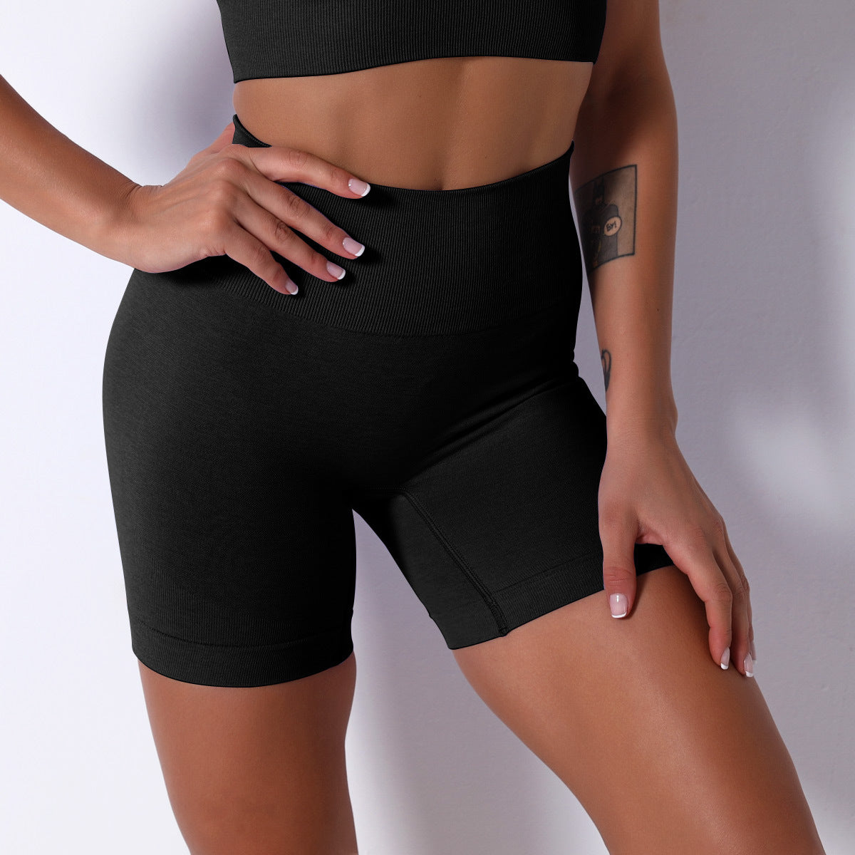 Person wearing black athletic shorts on a plain background